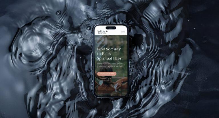 A mockup of a mobile phone floating on dark water, showcasing the Goddess Retreats website design.