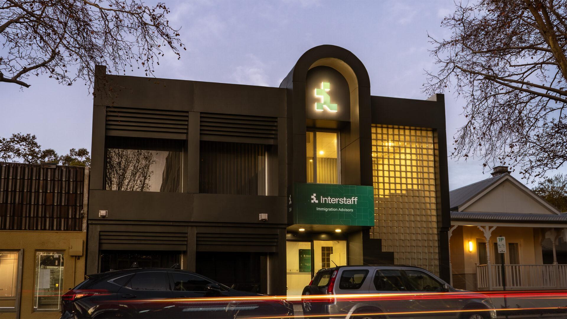 The exterior of the Interstaff Subiaco head office at dusk, featuring illuminated brand signage.