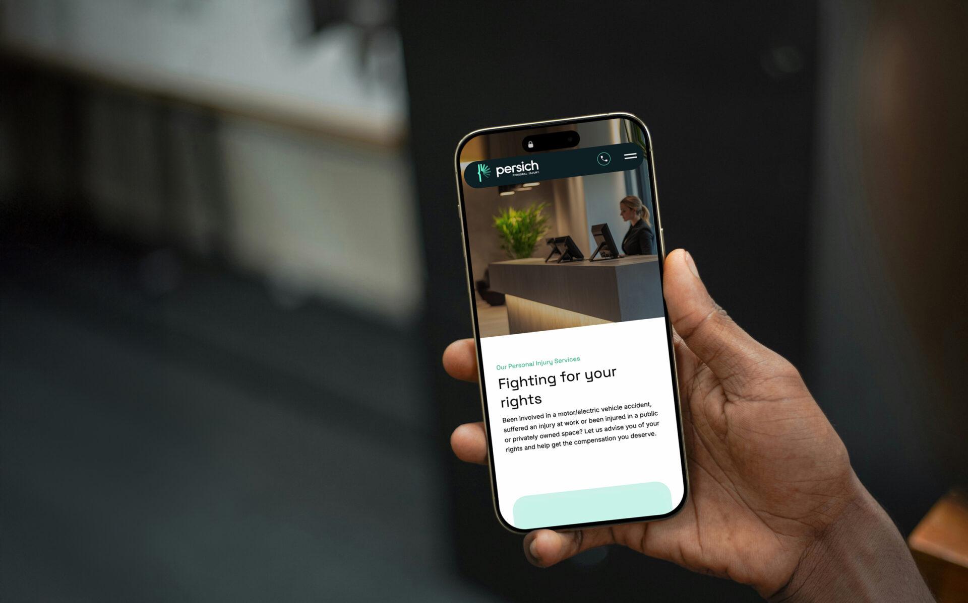 A mobile phone being held, featuring the mobile web design for Persich.
