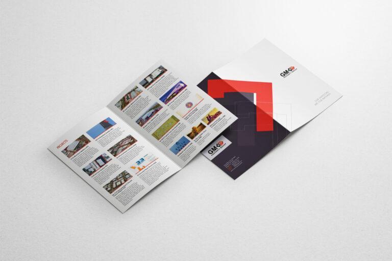 A GM Property Group brochure showing various projects lays open on top of a branded document folder.