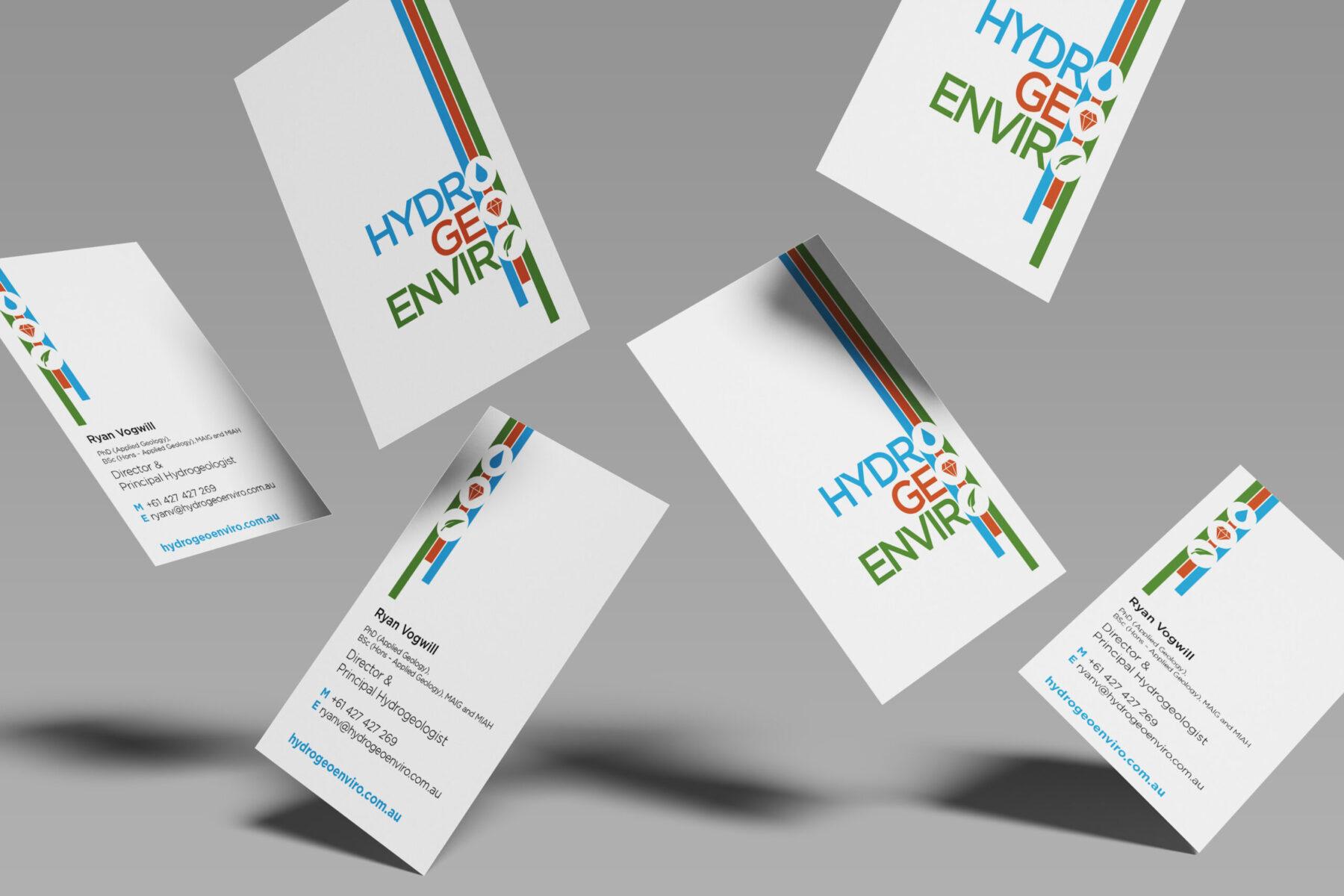A mockup of Hydro Geo Enviro business cards floating in mid-air, showing the company logo and professional contact design.