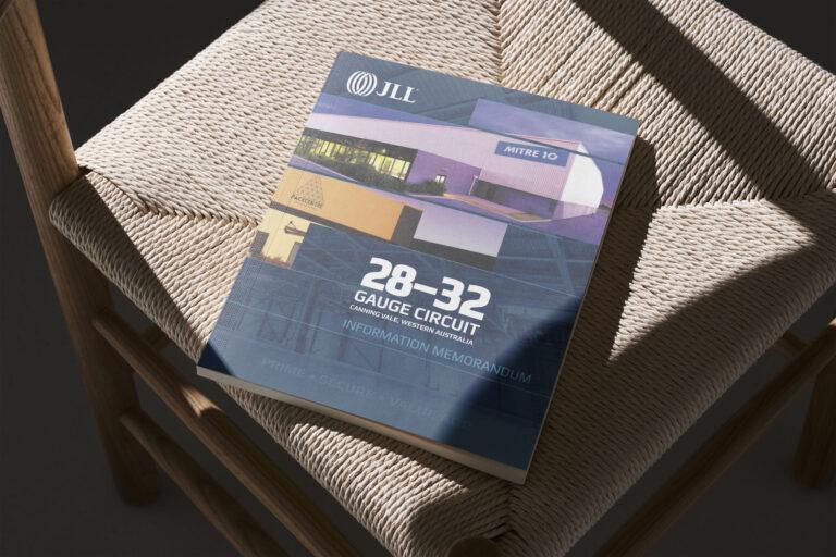 A JLL Information Memorandum magazine lies on a thatched chair, showcasing its cover design.