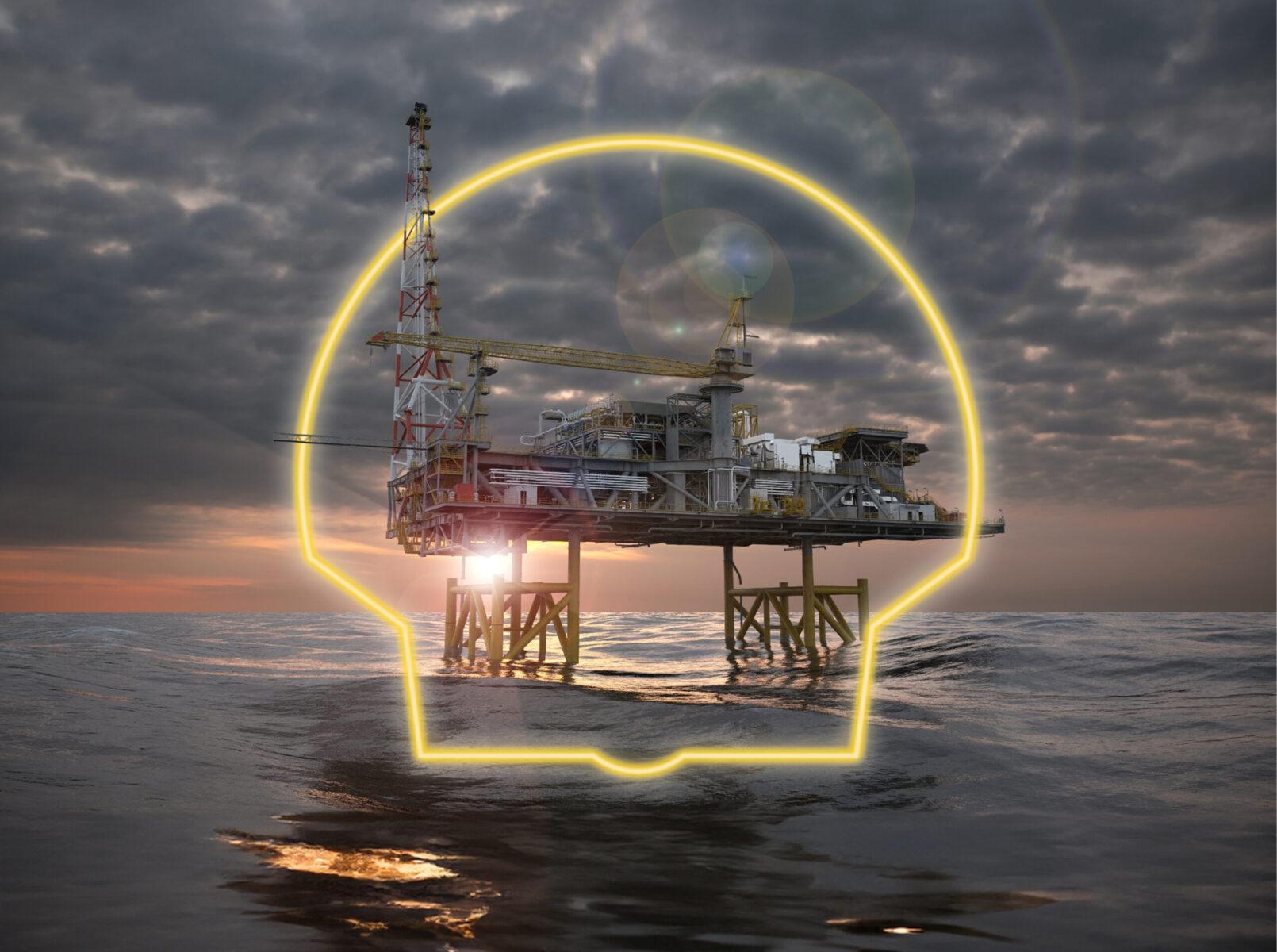 An oil rig over an open ocean with a cloudy dark sunset. The Shell logo is placed in the scene, masked behind and infront of the oil rig.