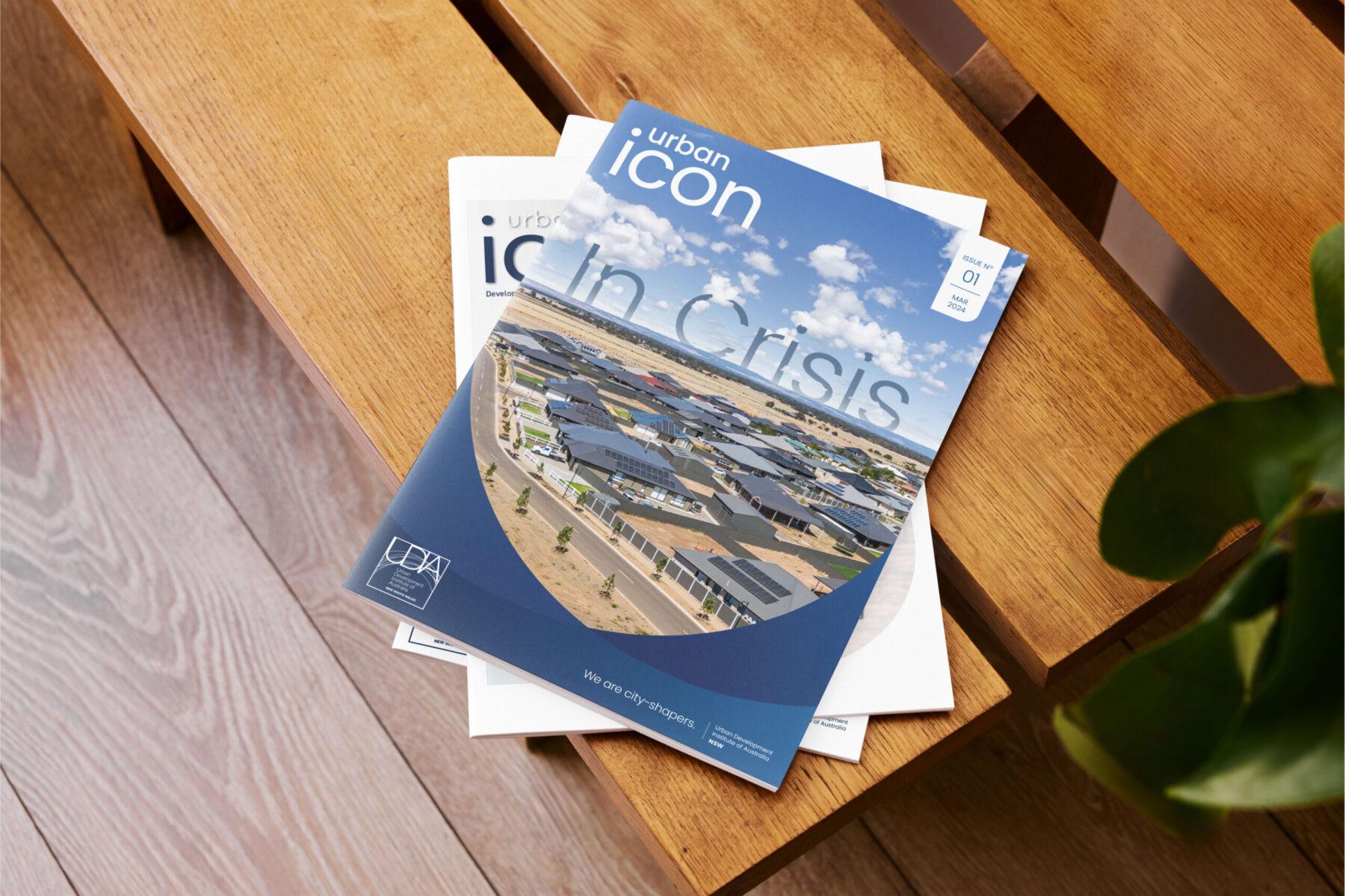 A stack of UDIA NSW magazines on a wooden table. The cover design is displayed with UDIA branding and professional layout.