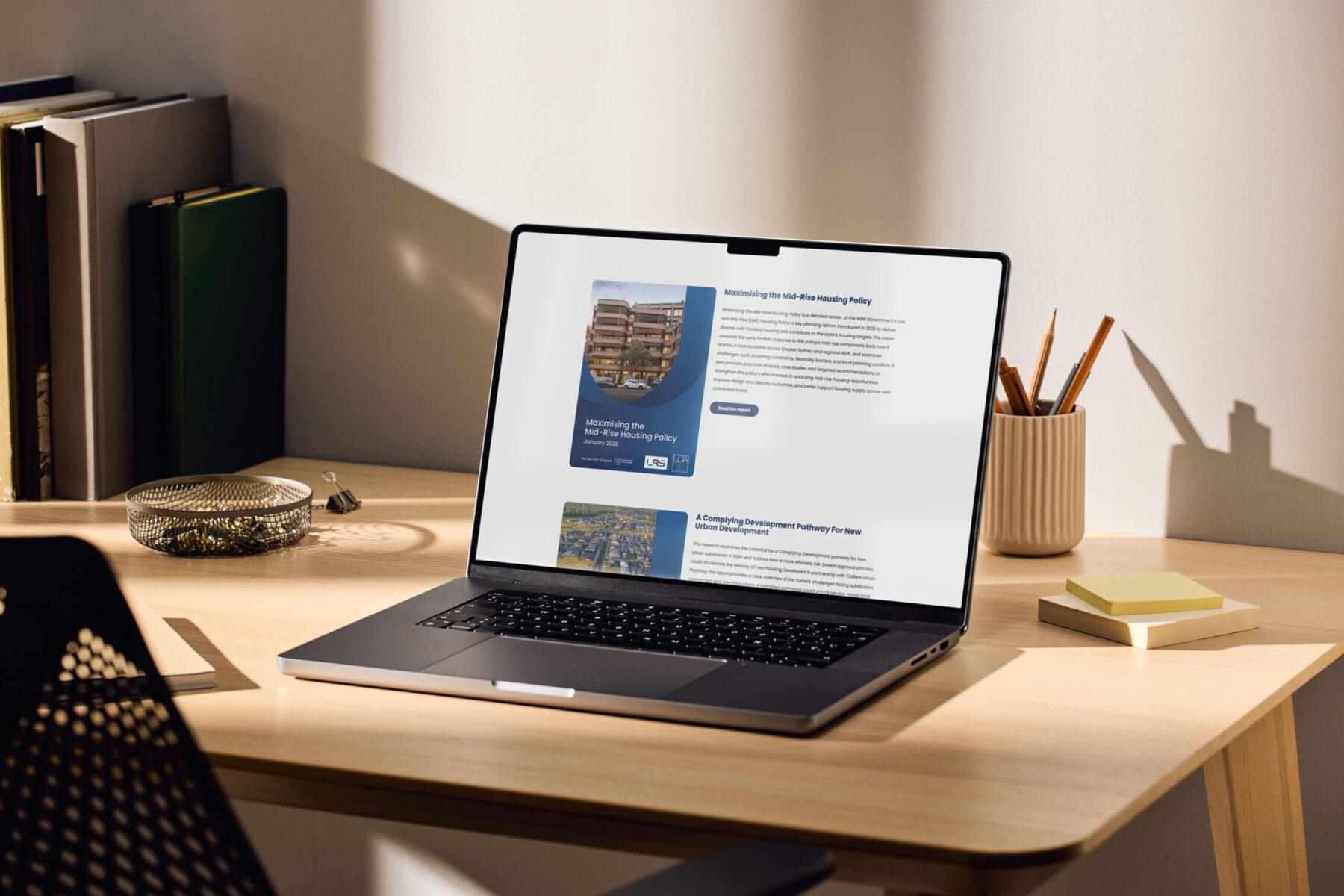 A mockup of a laptop on a desk, displaying an example web page design for the UDIA NSW website.